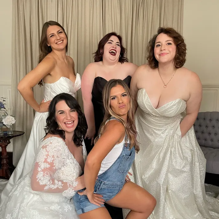 5 members of the Blue Sage Bridal Team wearing wedding dresses and smiling.