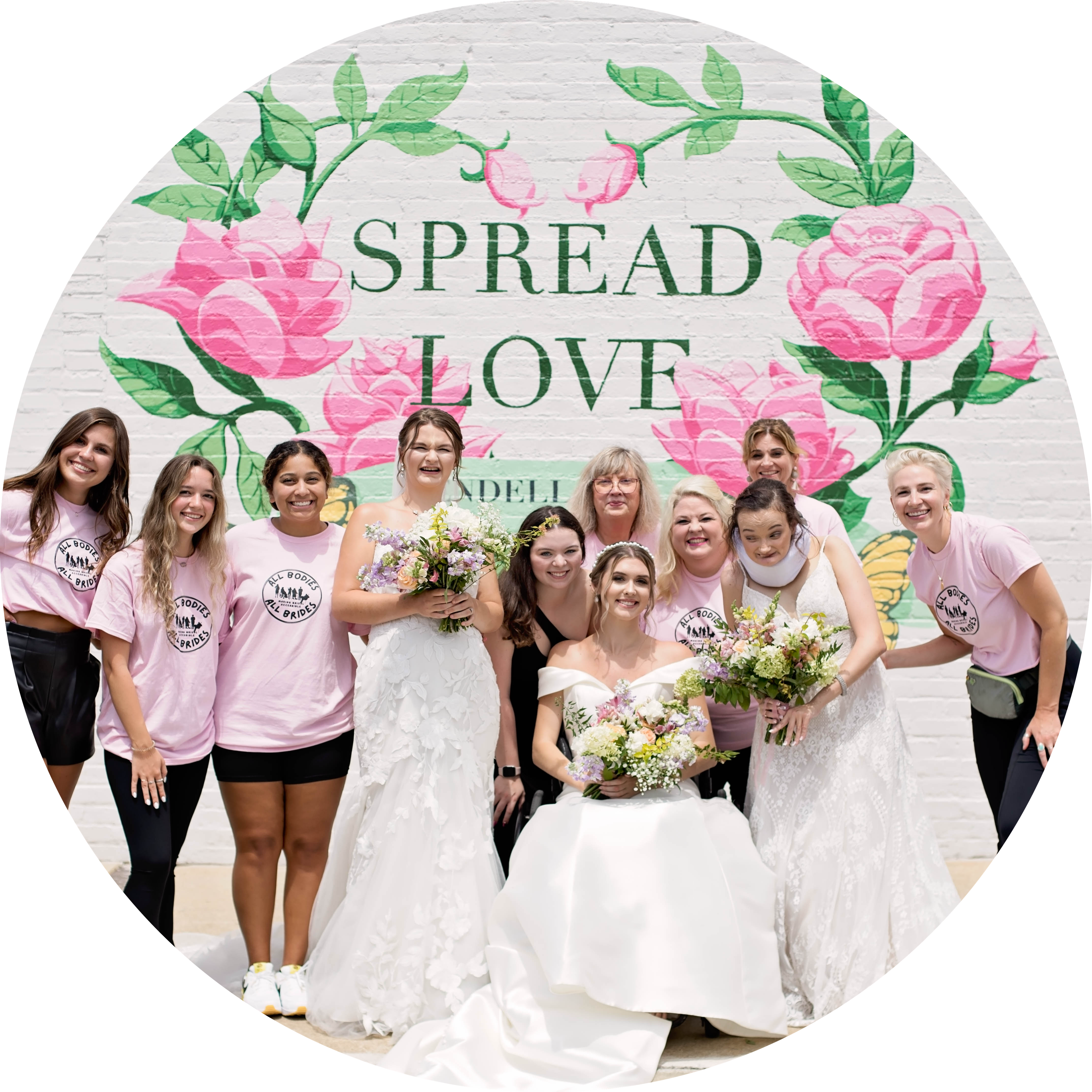 Volunteers and models from Simply Blush photoshoot, smiling in front of a mural reading "Spread Love"