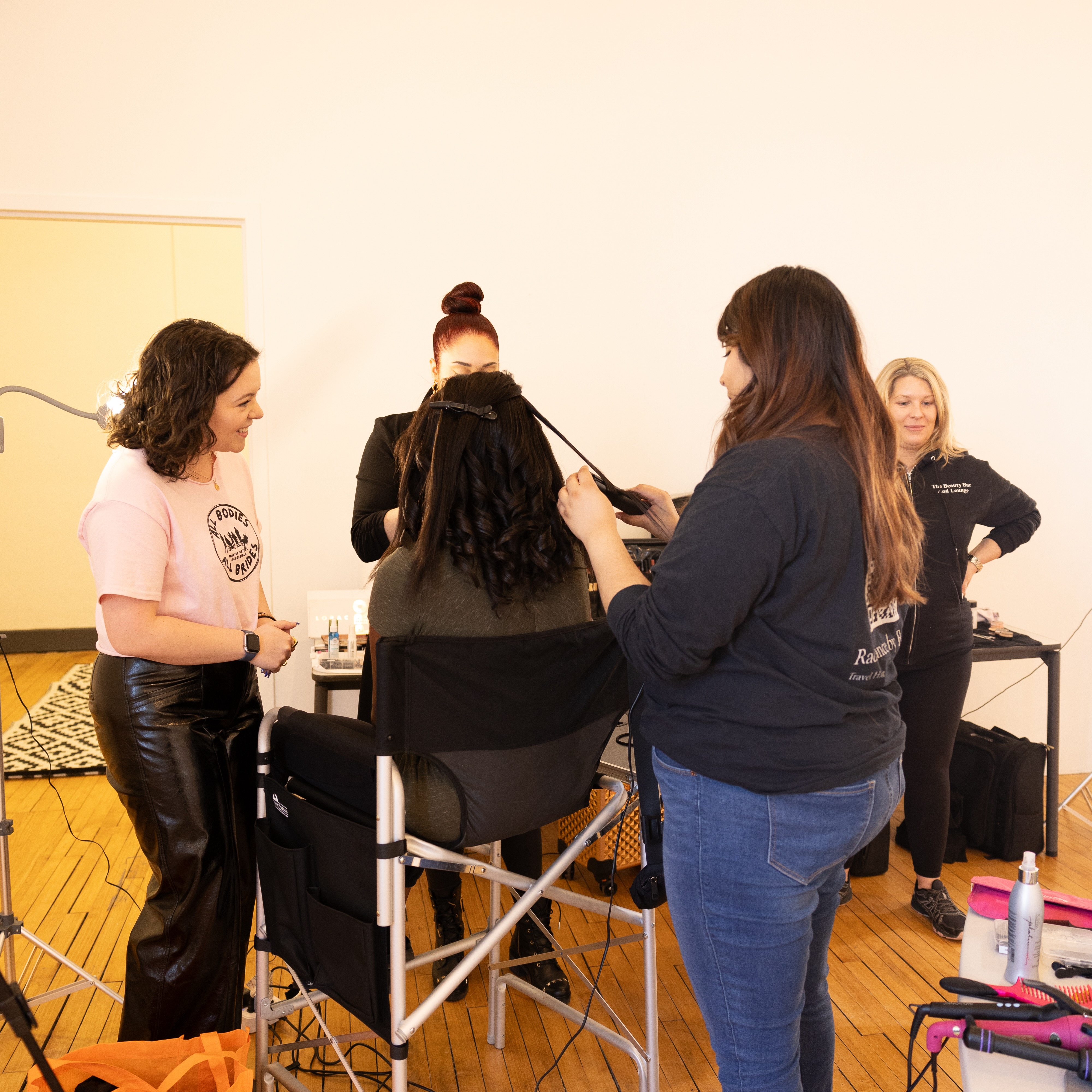 Group of 5 people, including founder Katie Horan, standing around a model getting her hair and makeup done.