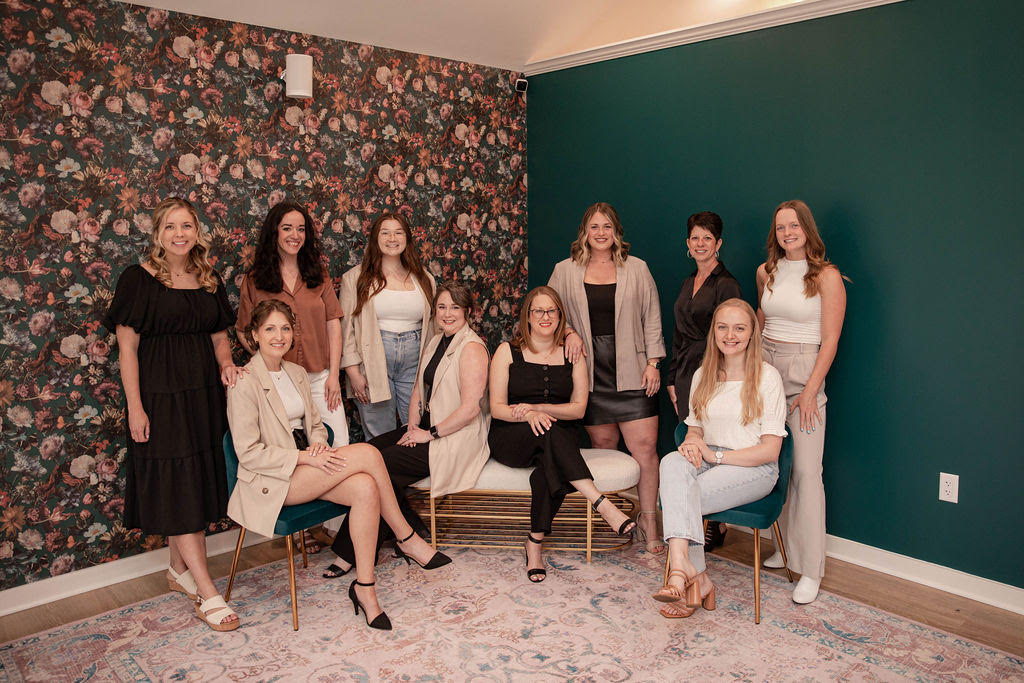 10 members of the Two Hearts Bridal team pose smiling indoors.